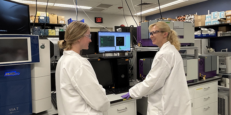 Two laboratory scientists conversing.